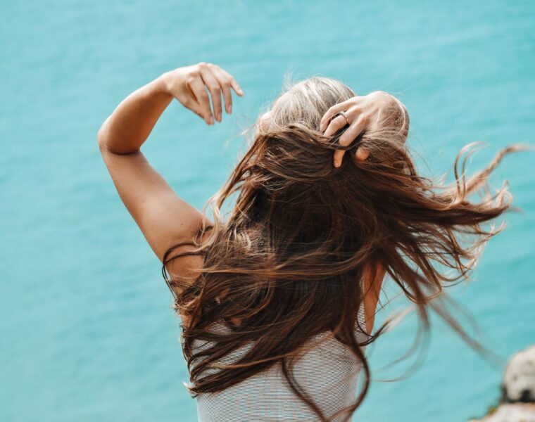 Tvoji porazi su tvoji dijamanti kultura femicida živim, back view photo of woman in white sleeveless shirt running her fingers through her hair