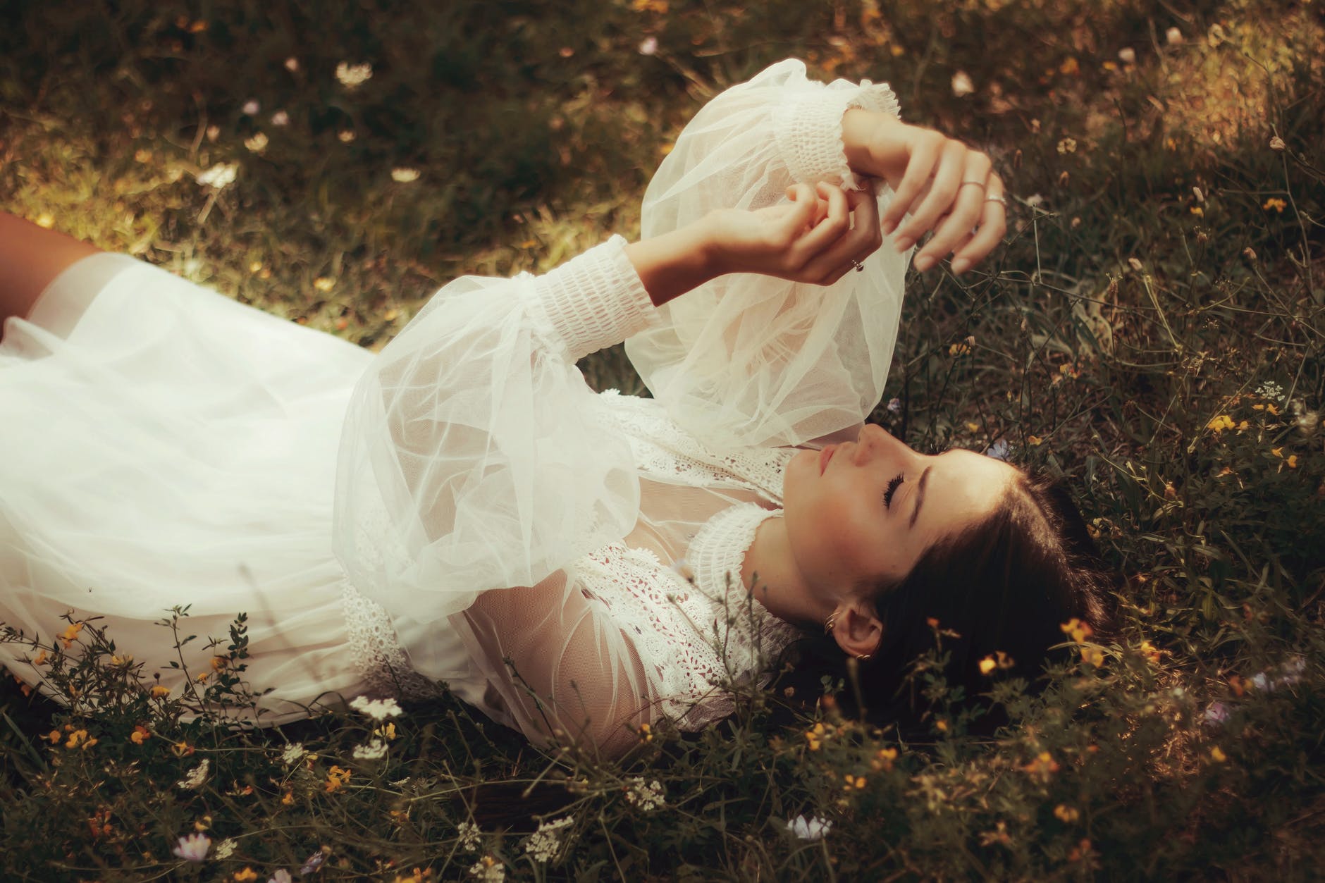 stylish woman in white dress resting on meadow