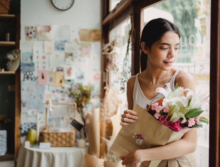 zaboraviti prošlost, calm woman with bouquet of flowers standing near door in shop
