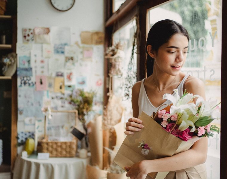 zaboraviti prošlost, calm woman with bouquet of flowers standing near door in shop