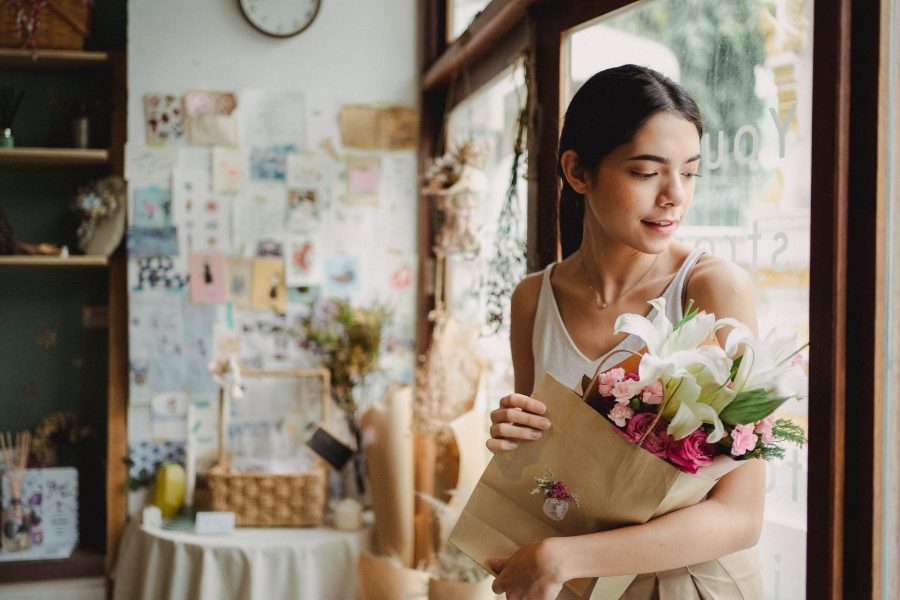 zaboraviti prošlost, calm woman with bouquet of flowers standing near door in shop