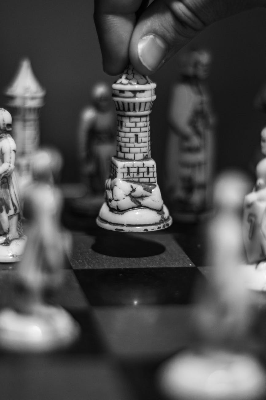 gray scale photo of person holding chess piece