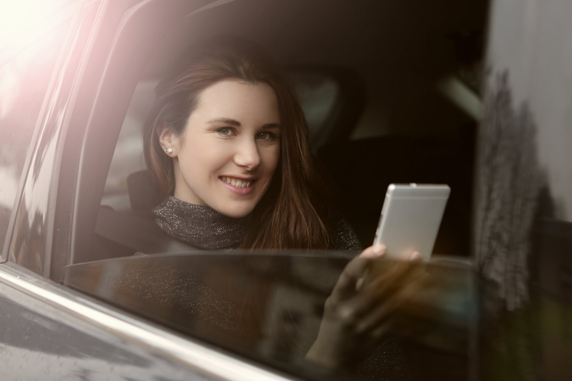 woman holding smartphone riding a black car