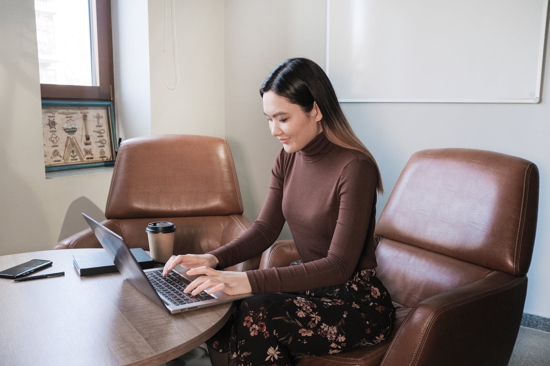 positive female employee typing on laptop in workspace
