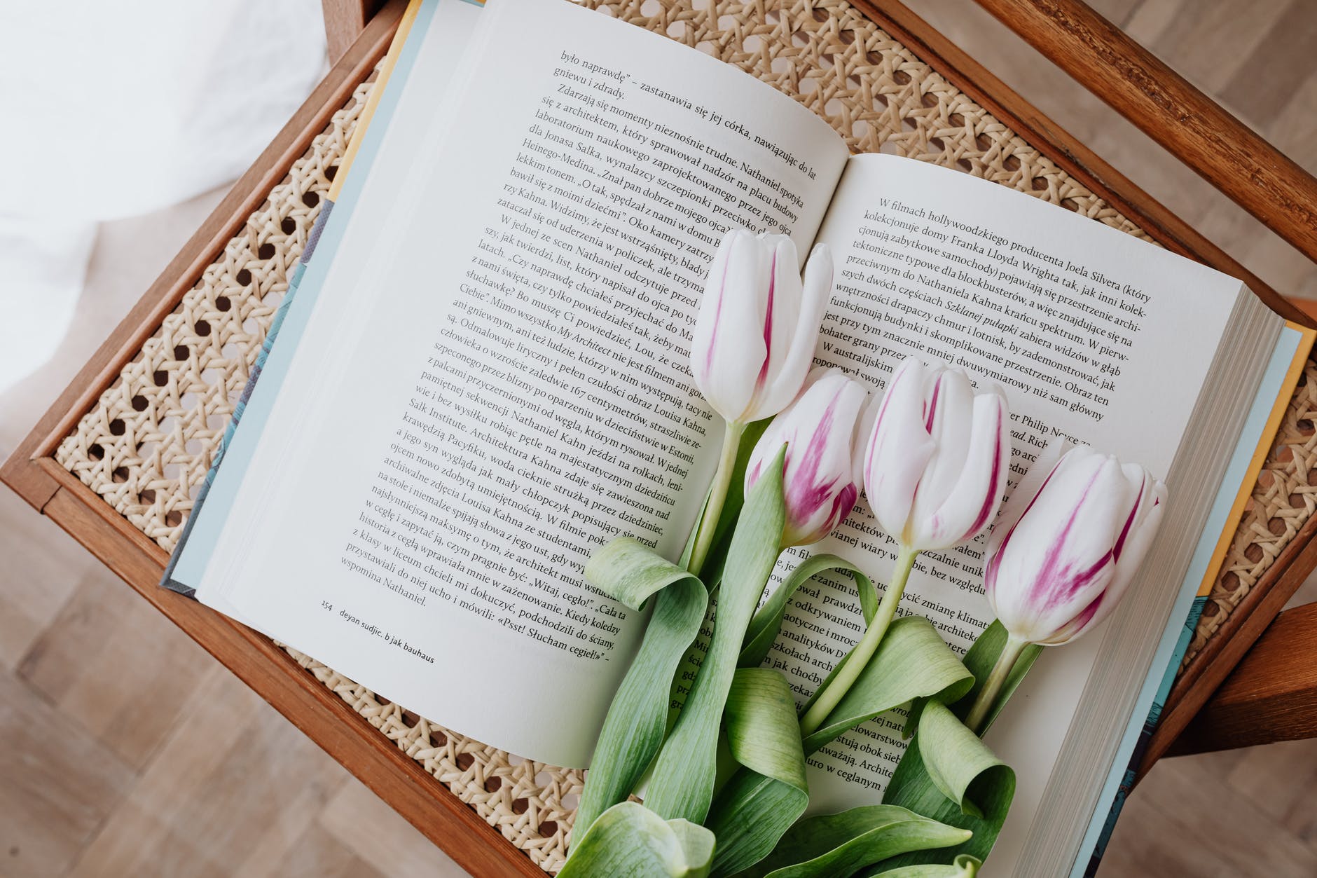 composition of fresh romantic flowers on open book arranged on vintage wicker table at home