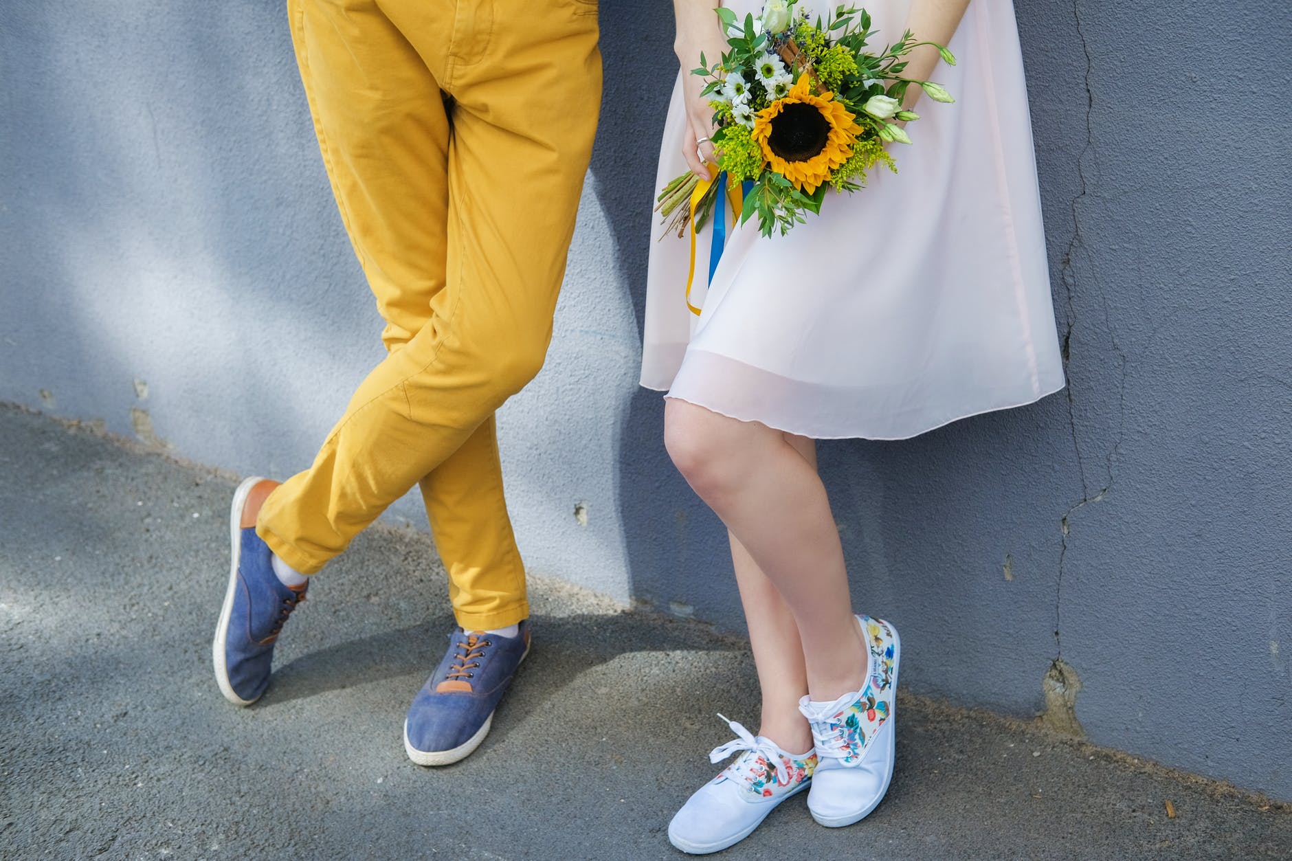 man in yellow pants and white nike sneakers holding yellow and red flower bouquet