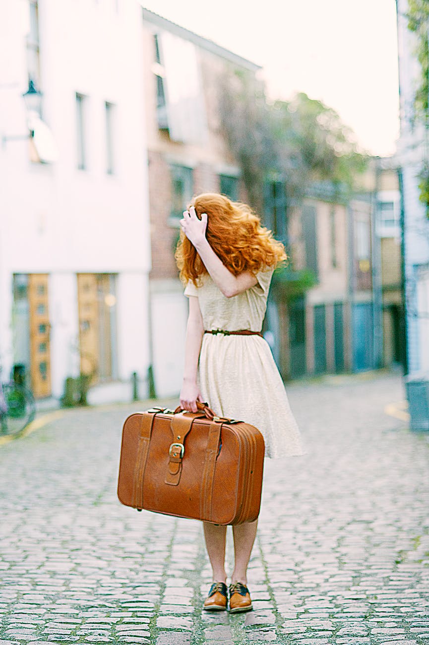 putovanja,

woman in white short sleeved dress holding brown leather suitcase