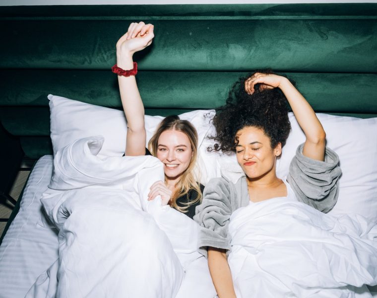 two young women lying on white bed