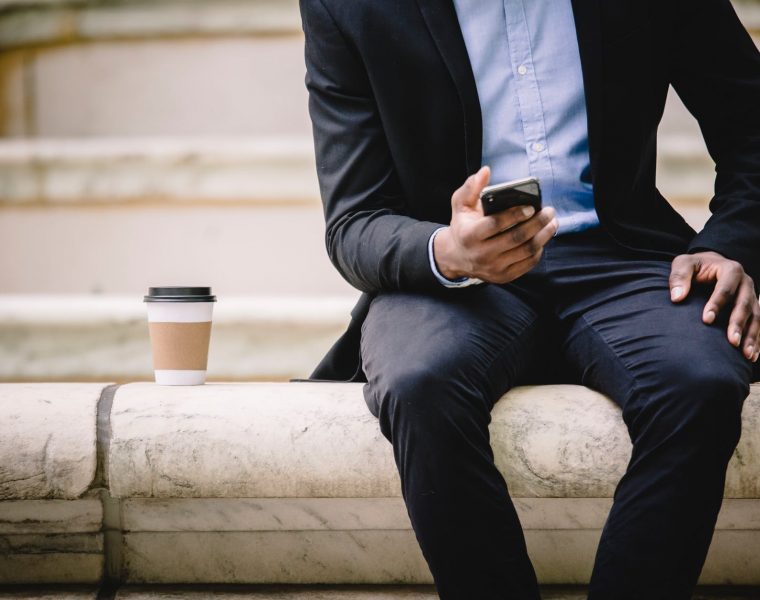 Jurica poželio podići kredit, Poduzetnička trubica: Jurica hrabro manevrira , crop businessman using smartphone while resting on bench with takeaway coffee