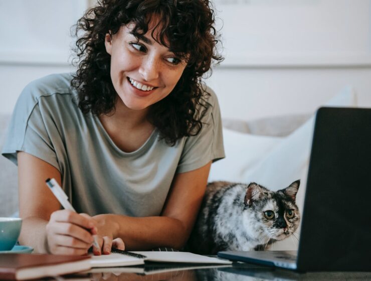 Lov na sreću i „high“ osjećaje , glad woman with cat writing in planner while using laptop