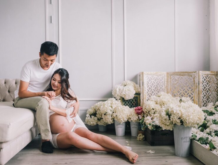 potraga za Bogom, smiling pregnant couple sitting in living room with flowers
