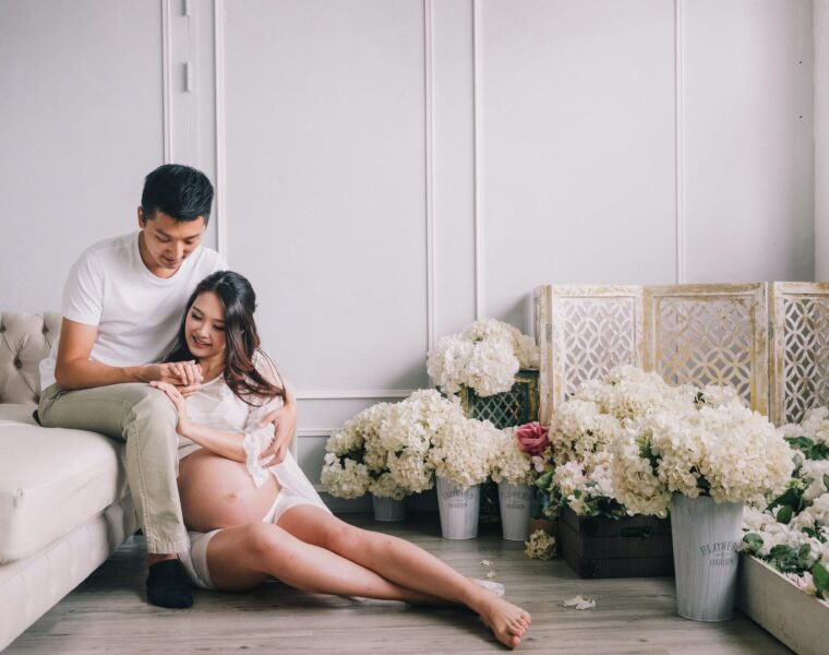 potraga za Bogom, smiling pregnant couple sitting in living room with flowers