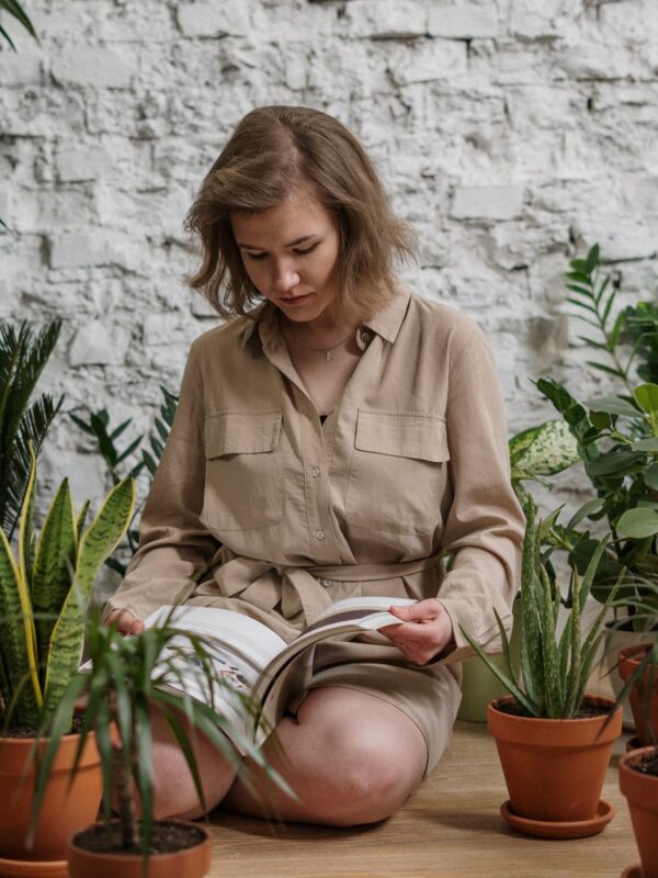 Patnja, woman sitting while reading book near potted plants