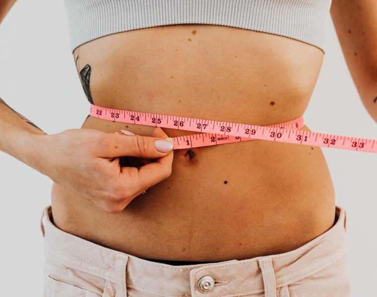 Otpuštanje suvišnih kilograma, woman measuring waistline with a pink tape measure