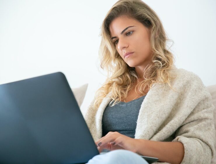 pad energije, woman sitting on sofa while using a laptop