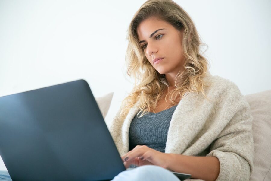 pad energije, woman sitting on sofa while using a laptop