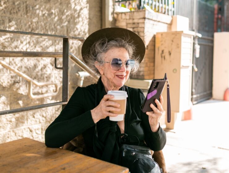 Starica (92), woman in black using her smartphone while having coffee