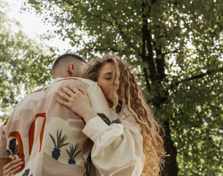 a man and woman hugging under a tree