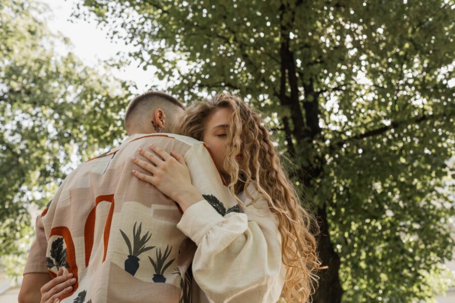 a man and woman hugging under a tree