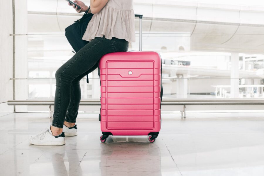 Bijeg od kuće, woman in white top and denim jeans sitting on red luggage bag