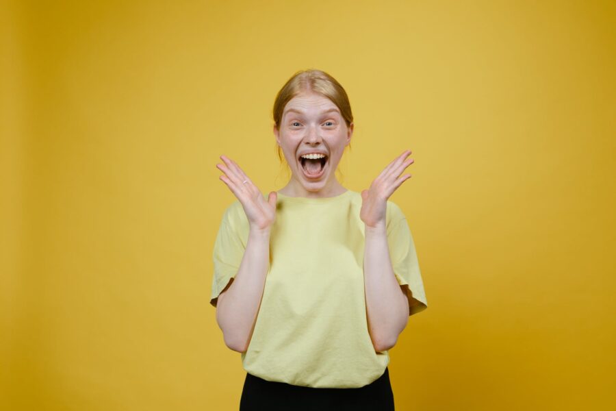 Žene koje puno galame žive duže, woman in yellow t shirt and black pants standing excited with open mouth