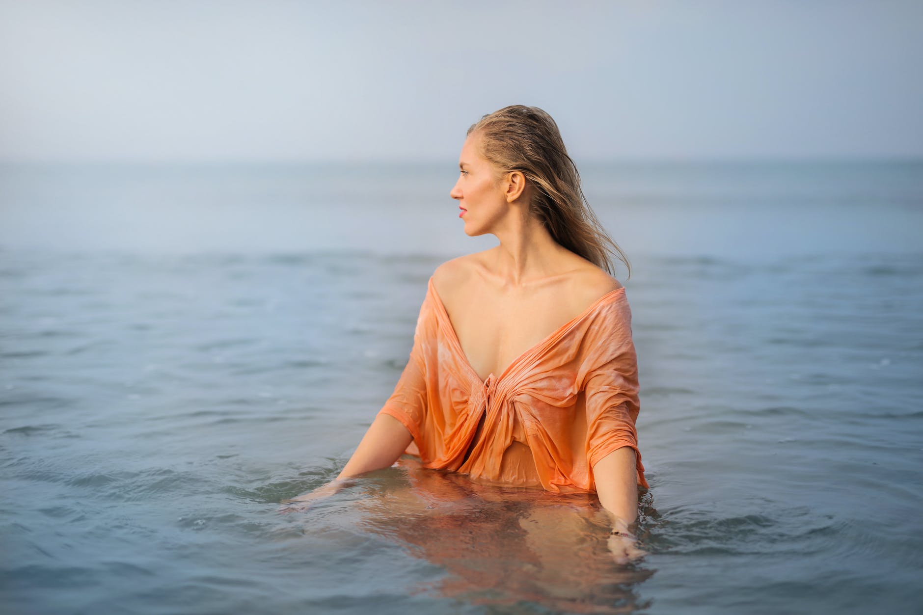 Otkad vjerujem sebi

photo of woman in orange top standing in body of water looking away