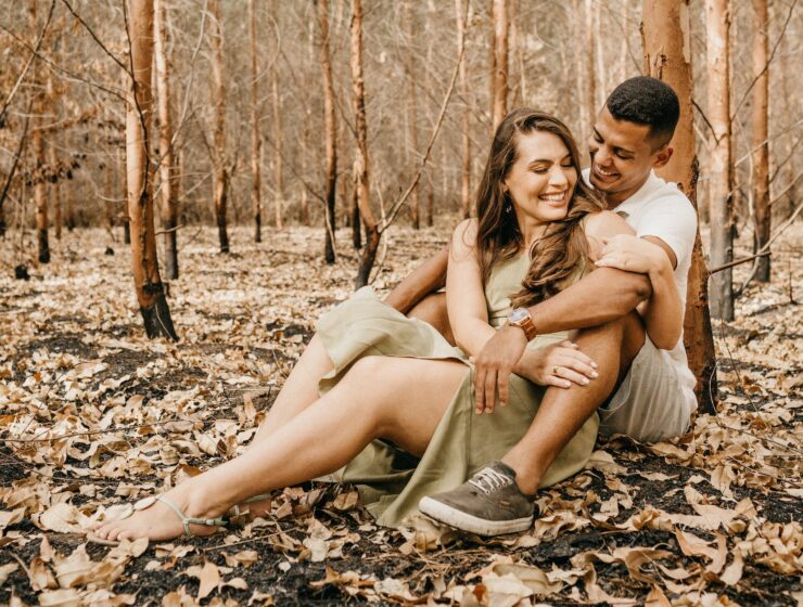 ljubavni horoskop za listopad, happy multiethnic couple hugging together sitting on dry leaves